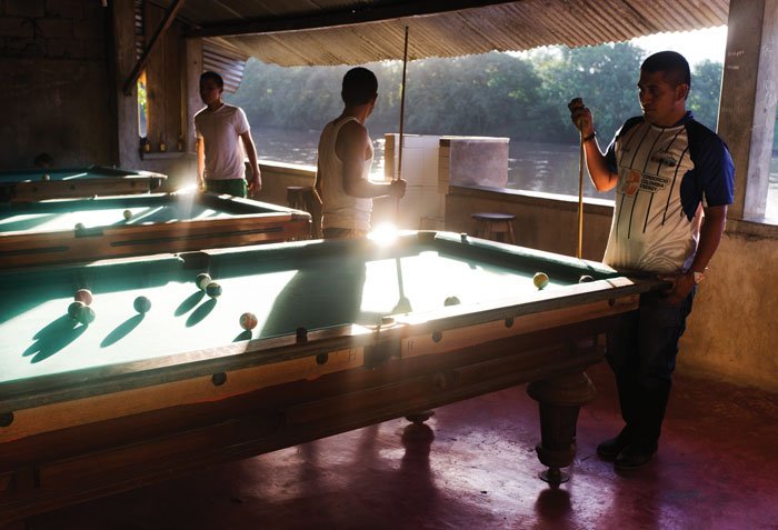 Misha Vallejo. La curiosidad ante todo. 2 Hombres juegan billar en un establecimiento en Puerto Nuevo, Sucumbíos.